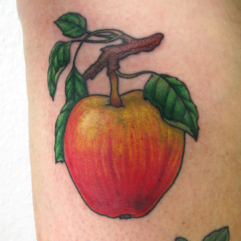 Botanisches Tattoo eines Apfel, der am Ast hängt. Am Ast sind 4 grüne Blätter. Der Apfel ist rot und grün-gelb. Obst Tätowierung.