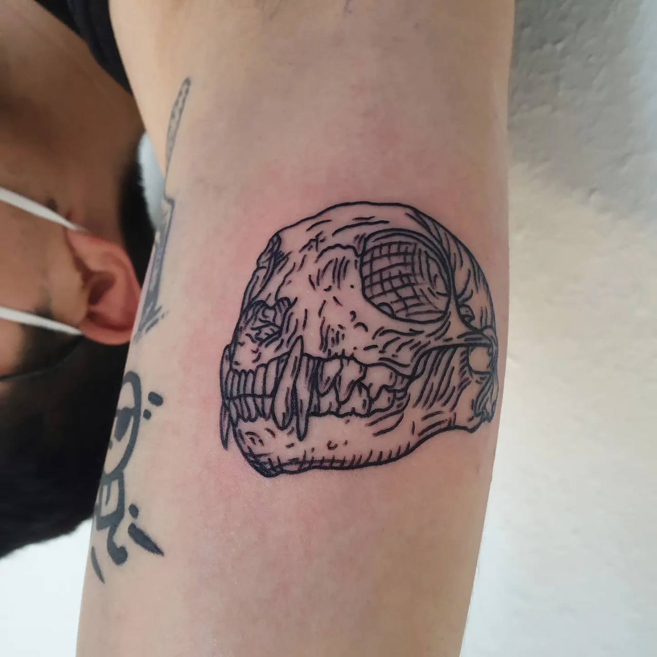 Schwarzes Holzschnitt Tattoo eines Katzenschädels. Ansicht seitlich von Vorne.