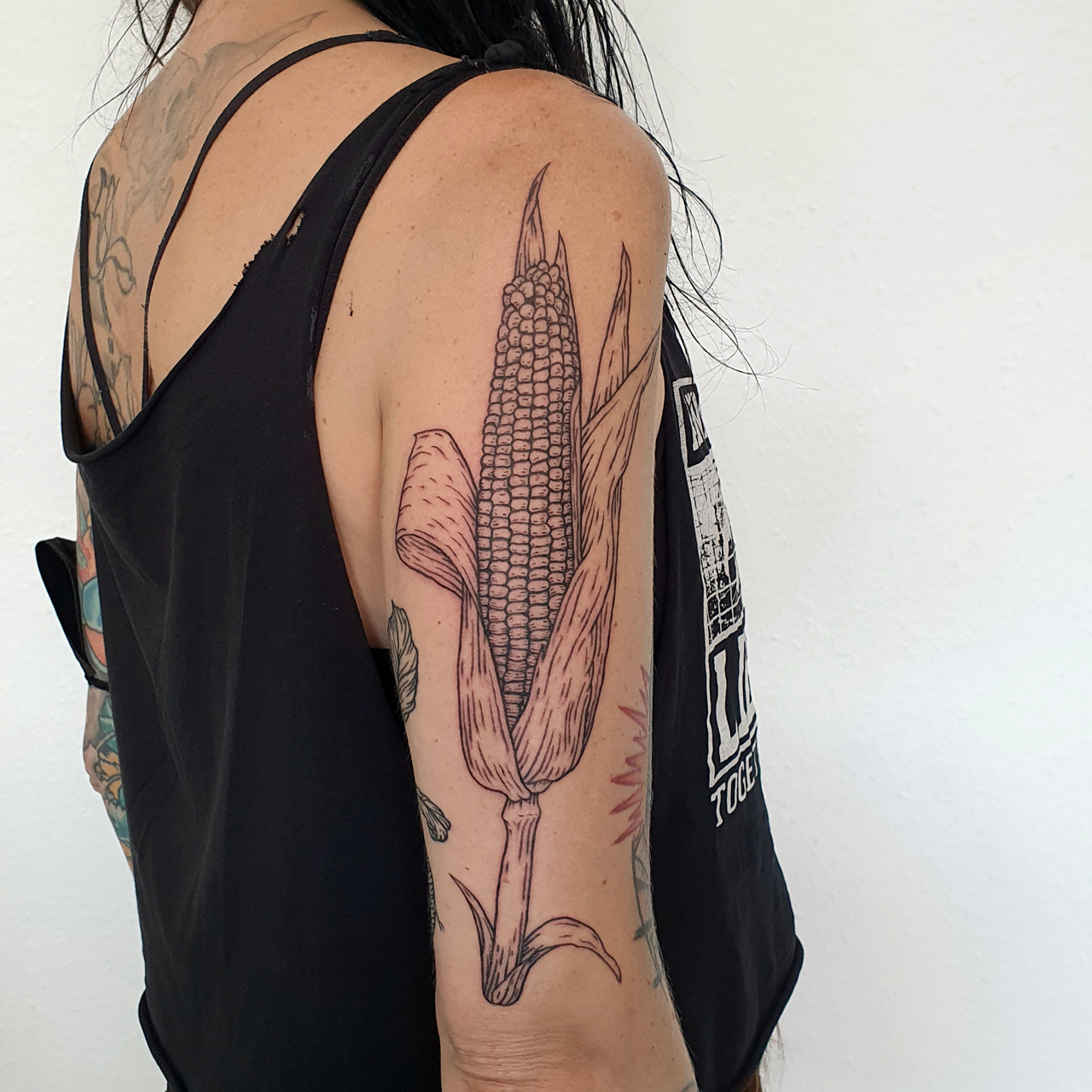 Schwarzes Holzschnitt Tattoo eines Maiskolben auf dem rechten Oberarm.