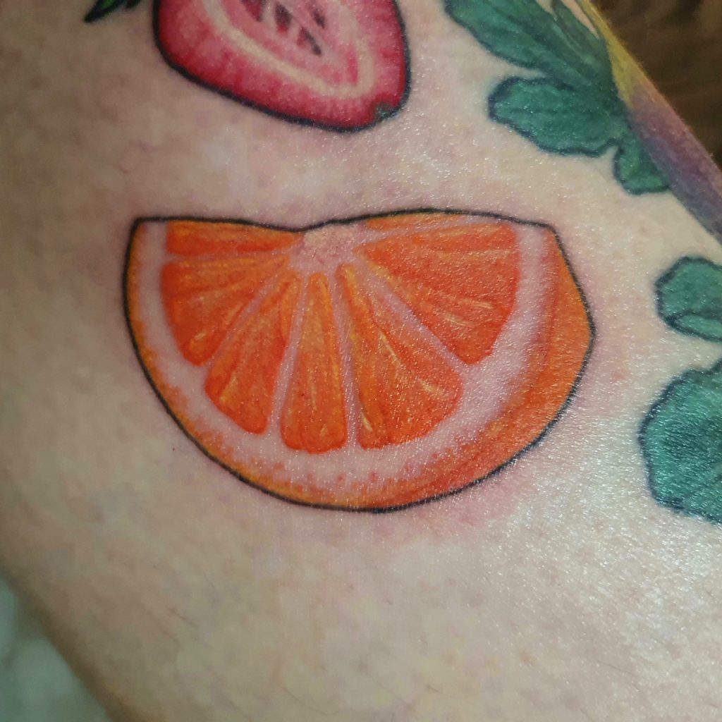 Tattos eines Orangenschnitz in orange, mit schwarzem outline. Obst Tattoo.