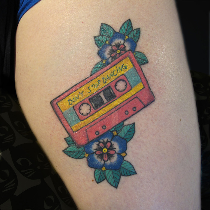 Colorful tattoo of a pink cassette with two blue flowers