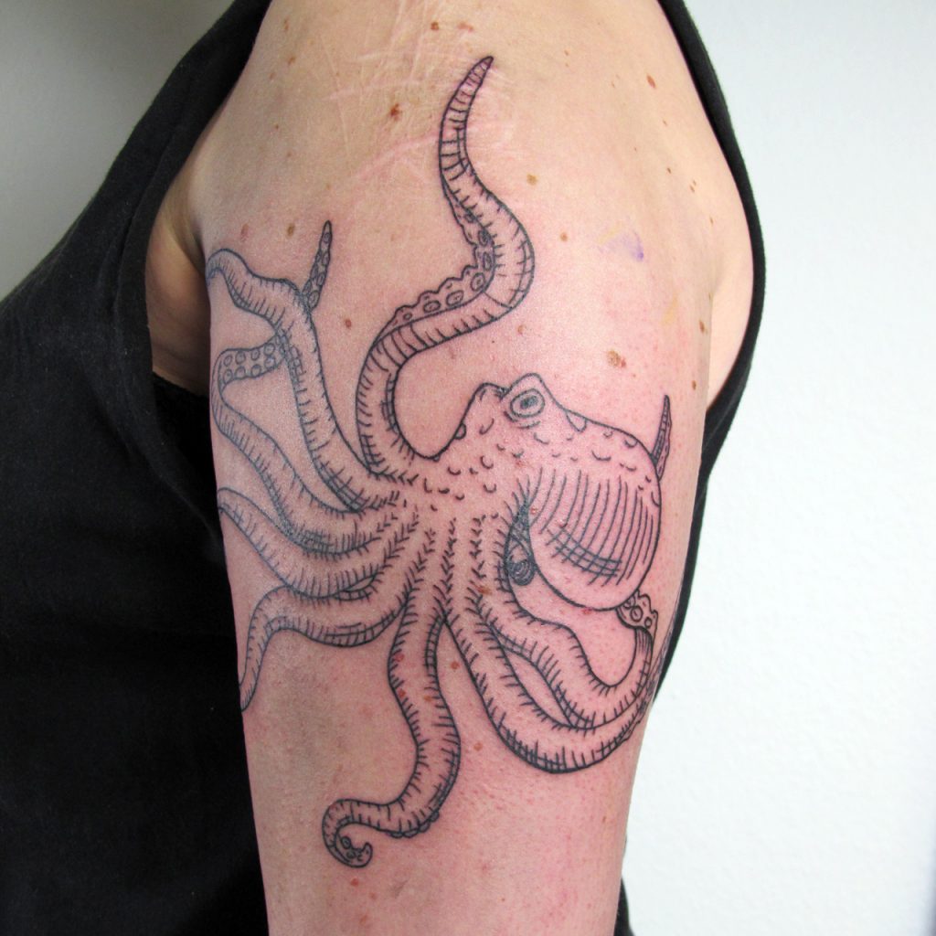 Octopus tattoo on upper arm covering scars in lineworktattoo and woodcuttattoo style