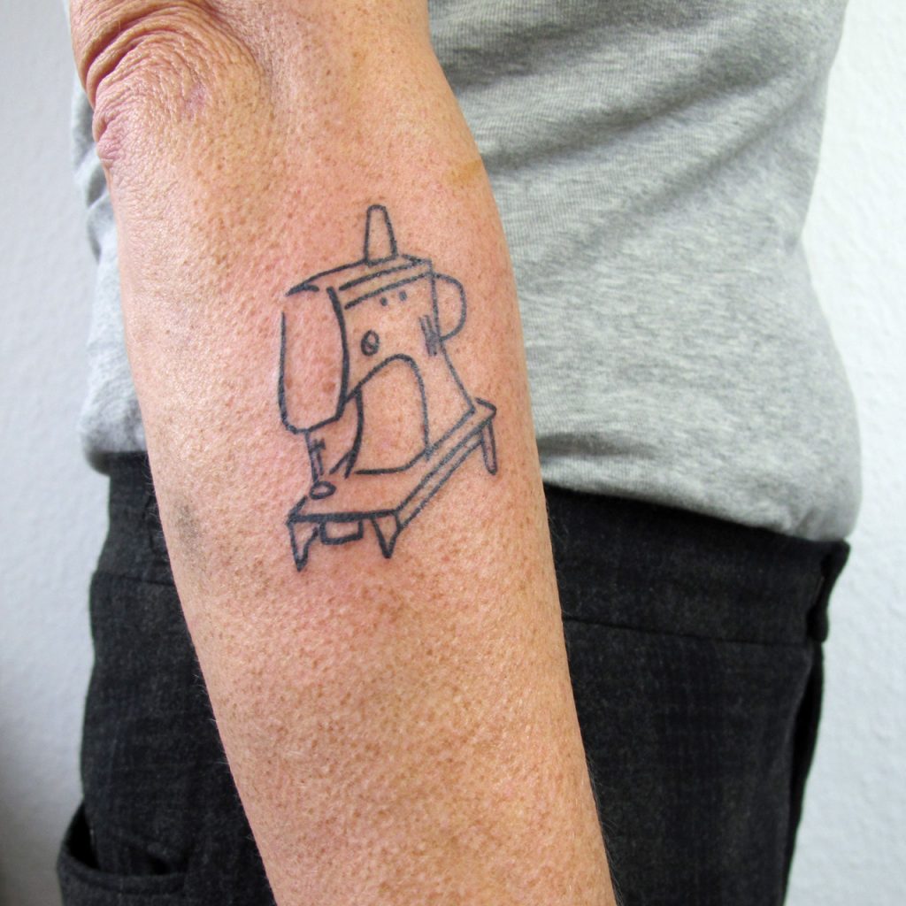 Small tattoo of sewing machine. Black. Ignorant style