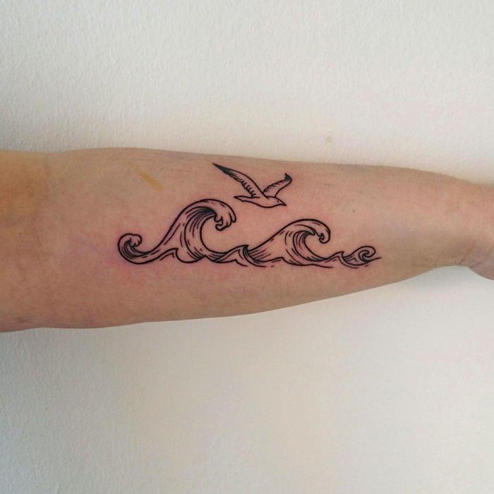 Tattoo on forearm of waves over which flies a seagull in lineworktattoo and woodcuttattoo style
