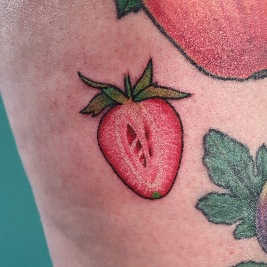 colorful tattoo of a strawberry cut open, botanical tattoo