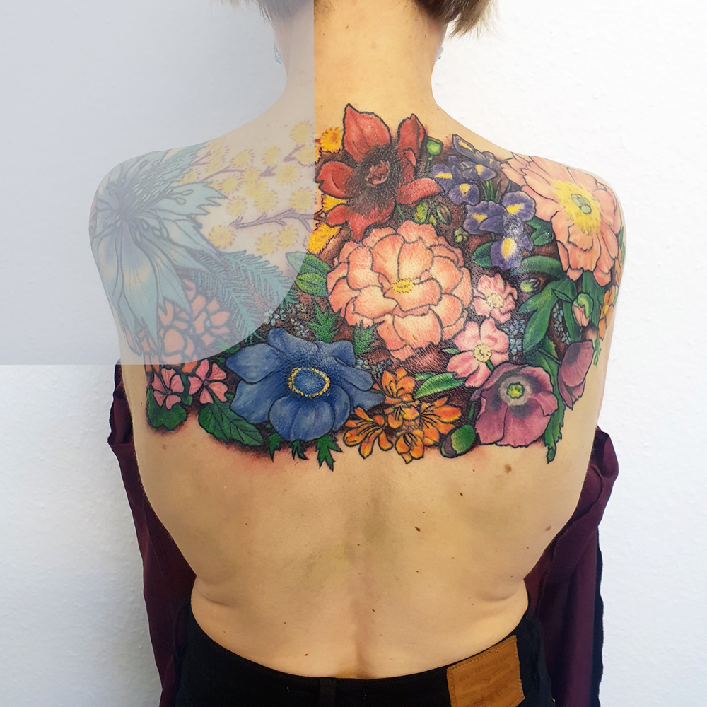 Colorful tattoo on upper half of back consisting of various flowers, e.g. peony, rose, poppy.